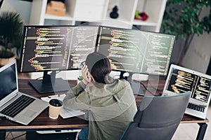 Young female programmer working at a desk with multiple computers coding software in a modern home office
