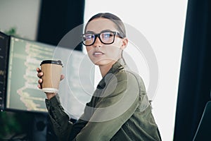 Young female programmer working from home office with a coffee cup, coding and developing software on her computer