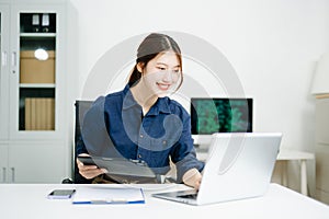 Young female programmer working with tablet and screen displaying code. Modern tech office setup, great for software, coding, IT