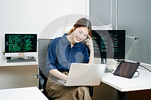 Young female programmer working with tablet and screen displaying code. Modern tech office setup, great for software, coding, IT