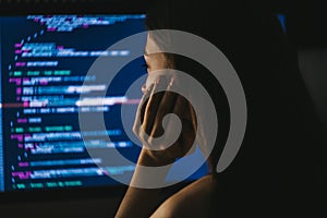 Young female programmer writes program code on a computer.