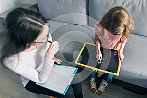 Young female psychologist talking with patient child girl in office. Mental health of children