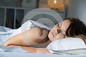 Young female in pygamas is sleeping on bed