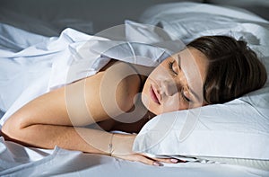 Young female in pygamas is sleeping on bed
