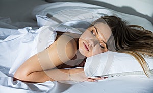 Young female in pygamas is sleeping on bed