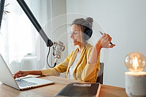 Young female radio host recording and broadcasting her podcast from homemade studio