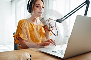 Young female radio host recording and broadcasting her podcast from homemade studio