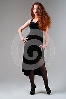 Young female with red hairs standing on grey background full len
