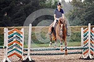A young female rider completing a jump