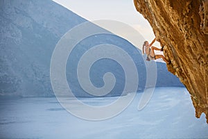 Young female rock climber on challenging route on cliff photo