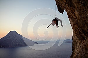 Young female rock climber hanging on rope while being lowered down