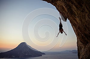 Young female rock climber hanging on rope upside down while being lowered down