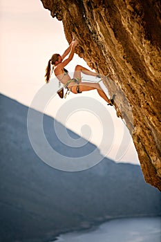 Young female rock climber wearing bikini on challenging route on cliff