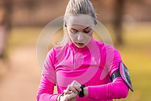 A young female runner checks the data on a smart watch after a sports performance