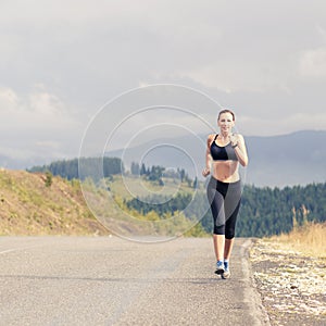 Young female runner on road cross in mountains
