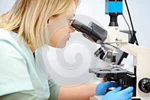 Young female scientist chemist or biologist analyzing new substance or virus in microscope. Woman in a laboratory for medical,