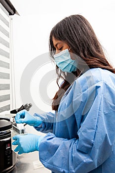 Young female scientist at the Immunohistochemistry laboratory carry out antigen retrieval on microscope slides with biopsy tissue