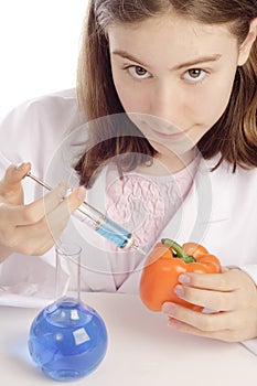 Young female scientist injecting an orange pepper