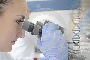 Young female scientist looking through a microscope in a laborat