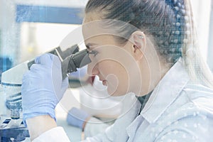 Young female scientist looking through a microscope in a laborat