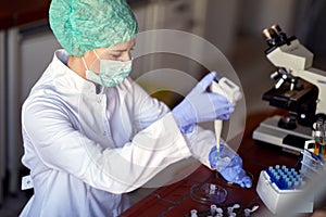 A young female scientist in a protective gear pipetting at the laboratory. Science, covid 19, virus, corona, chemistry, lab,