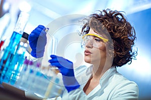 Young female scientist in protective glasses and gloves