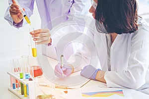 Young female scientist standing with techer in lab worker making