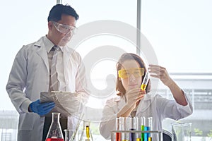 Young female scientist standing with techer in lab worker making