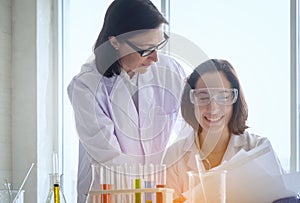 Young female scientist standing with techer in lab worker making