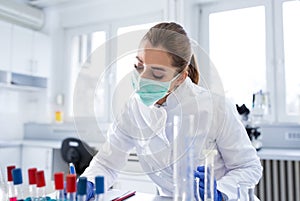 Young female scientist taking notes researching in lab