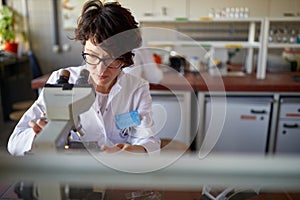 A young female scientist uses the microscope in the university laboratory. Science, chemistry, lab, people
