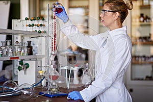 A young female scientist using an apparatus for the experiment at the university laboratory. Science, chemistry, lab, people