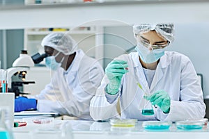 Young female scientist working with colored samples doing research in laboratory