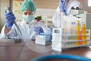 Young female scientists in protective gear carefully working with chemicals in a laboratory. Science, chemistry, lab, people