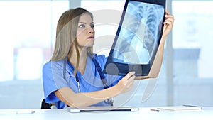 Young Female Serious Doctor Examing X-ray of Patient, Lungs and ribcage