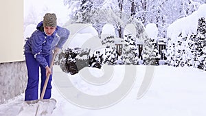 Young female shoveling near own house after snowfall