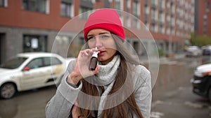 Young female sick woman, girl uses a nose spray at street outside, healthcare, flu, people, health, disease, pain