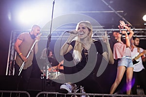 Young female singer performing with musicians at nightclub during music festival