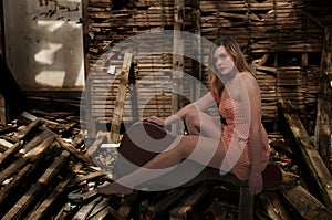 Young female sitting on an acoustic guitar case in a broken abandoned wooden room