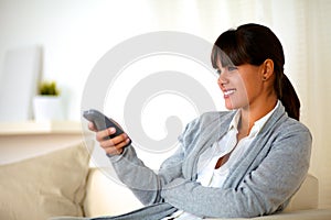 Young female sitting on couch with remote