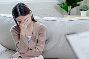 Young female sitting with her hands covering her face, feeling stressed and worried. Unhappy asian woman sitting alone. Sad women