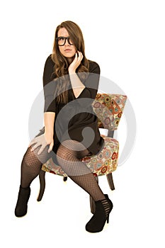 Young female sitting in a nice floral chair wearing black glasses