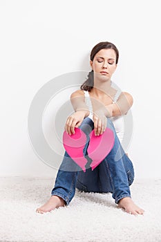 Young female sitting with paper heart in hand