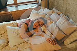 Young female sleeping peacefully in her bedroom, relaxing. Calm and peaceful woman sleeping in bed. Woman asleep at home
