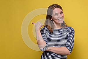 Young female smiling cheerfully and pointing with forefingers left