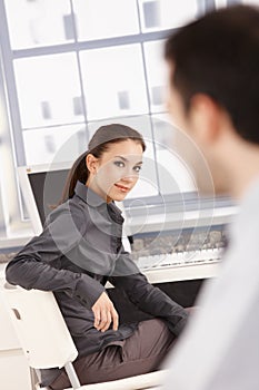Young female smiling at her colleague in office