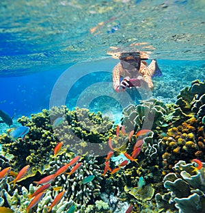 Young female snorkler, takes pictures of the underwater world