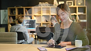 Young female software programmer or coder working in startup company and colleagues sitting in background