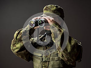 Young female soldier observe with binoculars. War, military, army people concept