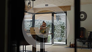 Young female is speaking on phone sitting at the table.